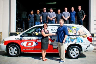 Dr. Louise Kelly accepts keys to the “Workout with The Man” van from Joe Pepiernik and members of Team Dumbell Man Service Department.